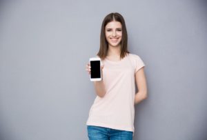 Happy young woman showing blank smartphone screen